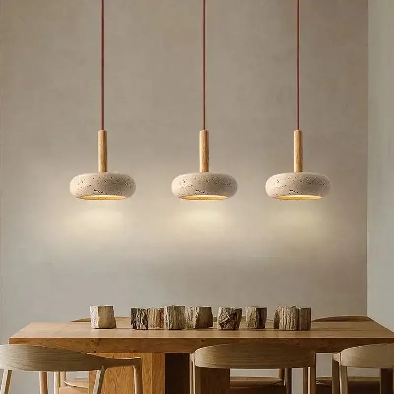 Three DecorBites™ yellow travertine stone pendant lights with wooden fixtures hang above a kitchen island dining table