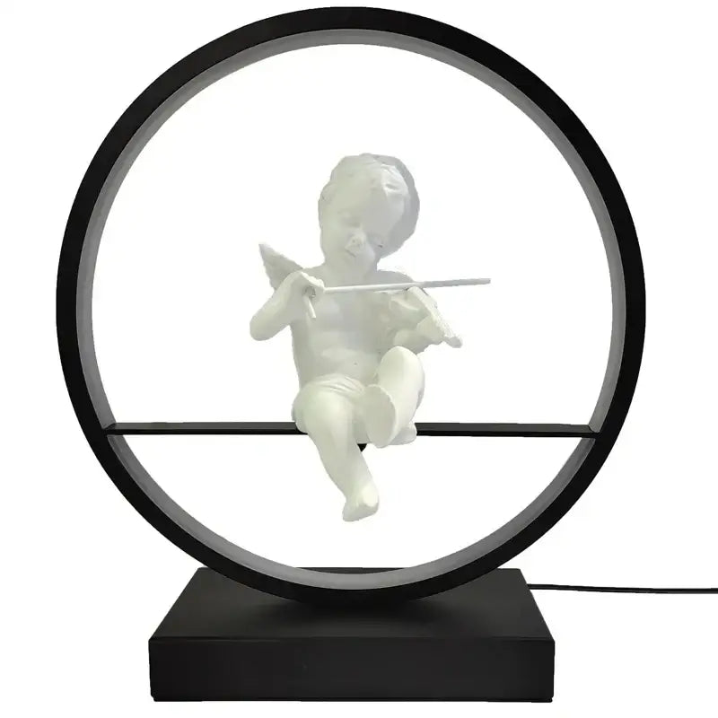 White cherub figurine playing flute inside black frame on dimmable angel table lamp by decorbites for bedroom decor