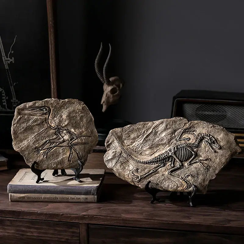 Two black stand mounted decorbites dinosaur fossil resin replicas displayed atop stacked books for office decor