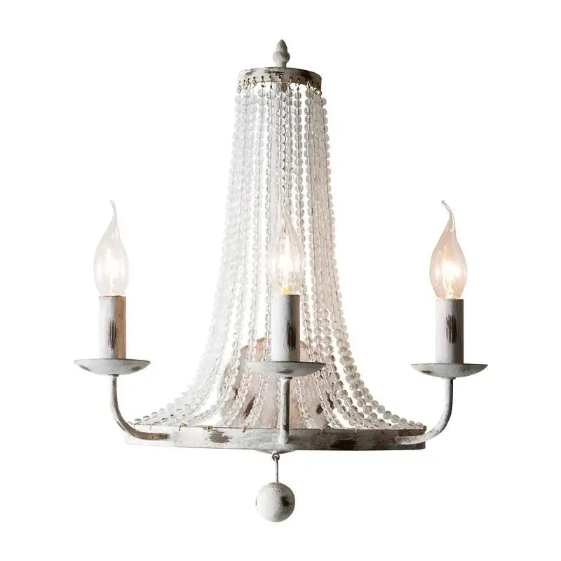 Delicate white distressed metal wall lamp with decorbites crystal tassel and three candle-style bulbs for bedroom decor