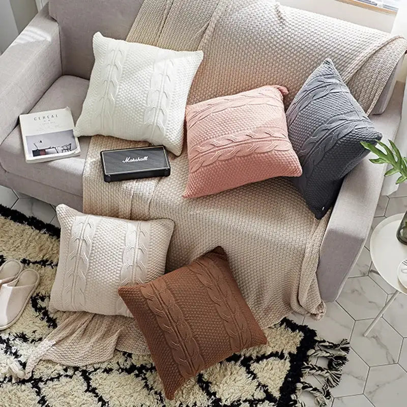 Set of five double cable knit cushion covers in cream, blush pink, slate gray, beige, and brown for living room use