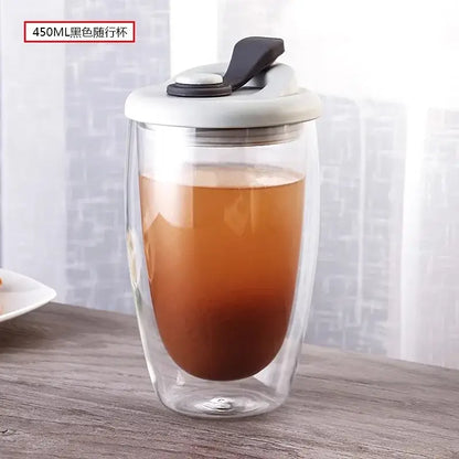 A clear double deck insulated glass travel mug with white and black lid filled with amber beverage