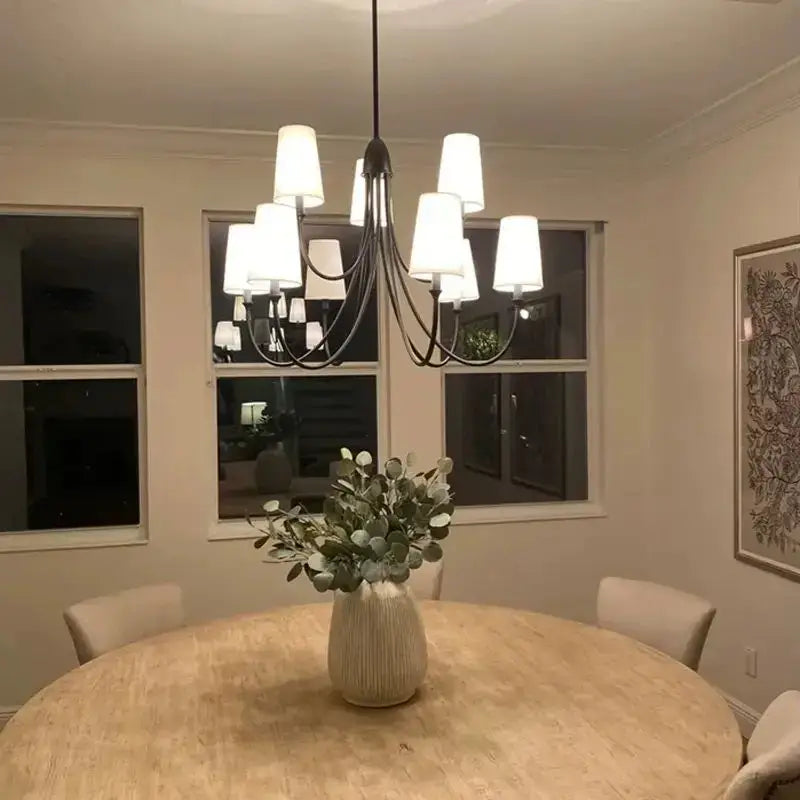 A modern black double layered minimalist wrought iron pendant light with white cylindrical shades above a dining table