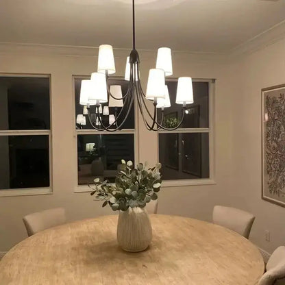 A modern black double layered minimalist wrought iron pendant light with white cylindrical shades above a dining table