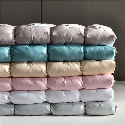 Stack of plush quilted down duvets in pastel lavender teal cream pink and gray filled with 95 white goose down