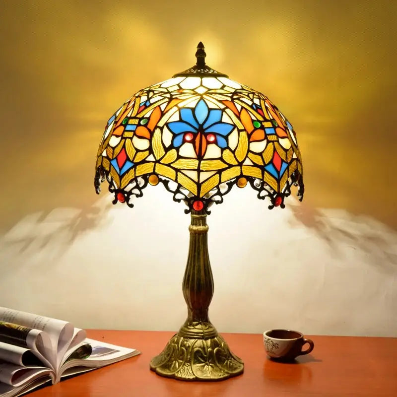 A decorbites dragonfly tiffany stained glass table lamp with a floral shade in blue orange yellow and red hues on a brass base