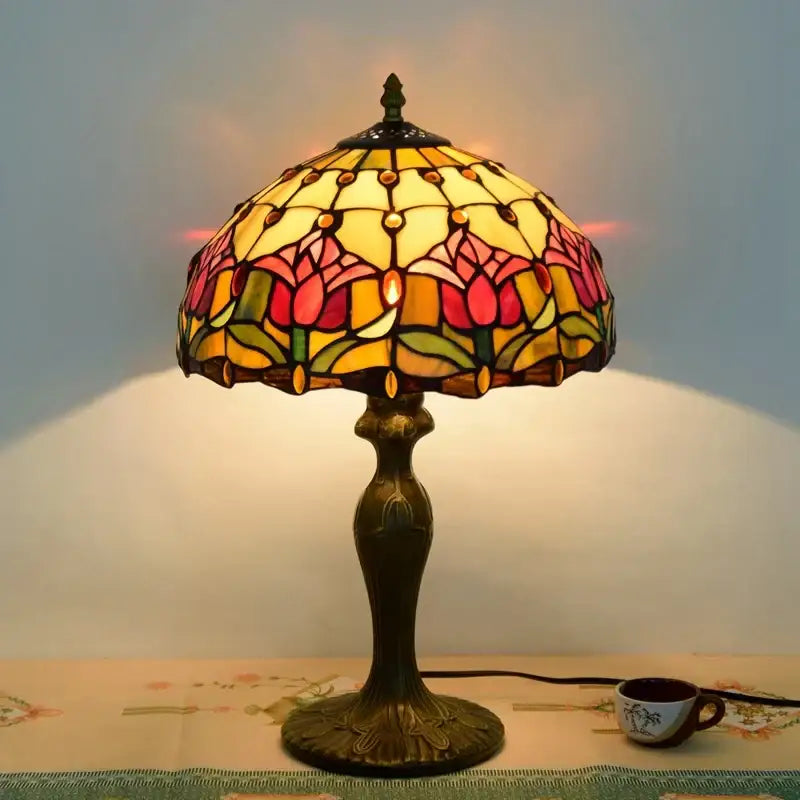 A dragonfly tiffany stained glass table lamp with pink and yellow tulip shade on an ornate brass decorbites dragonfly tiffany base