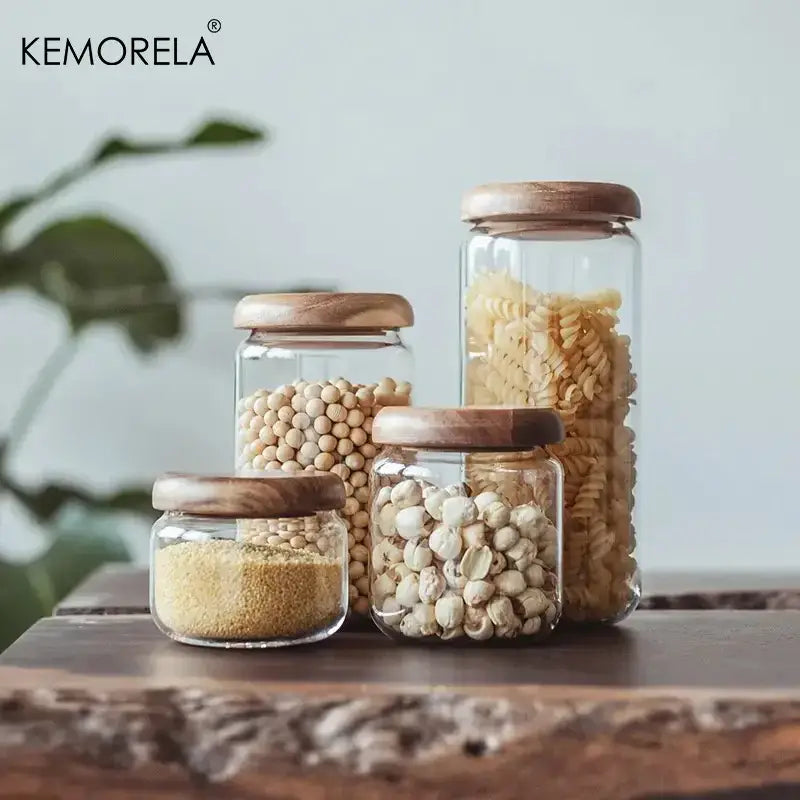 Set of clear glass food storage jars with elegant acacia wood lids holding assorted dry goods for kitchen use