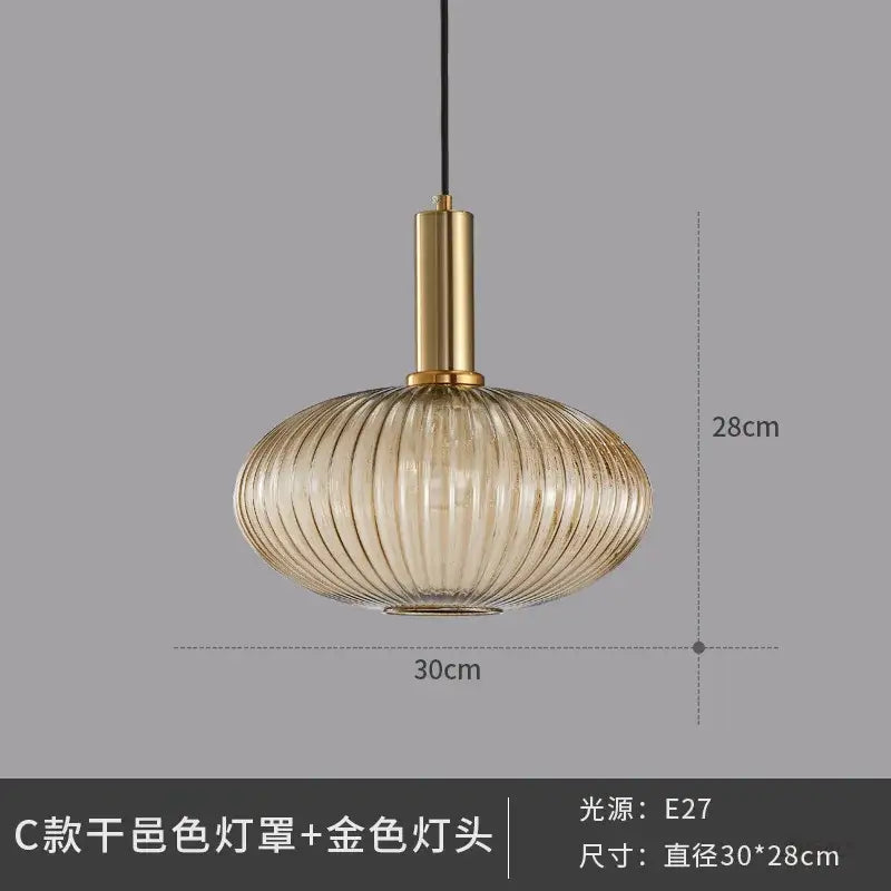 A modern glass pendant light with a ribbed translucent amber shade and polished gold metal fixture for dining room