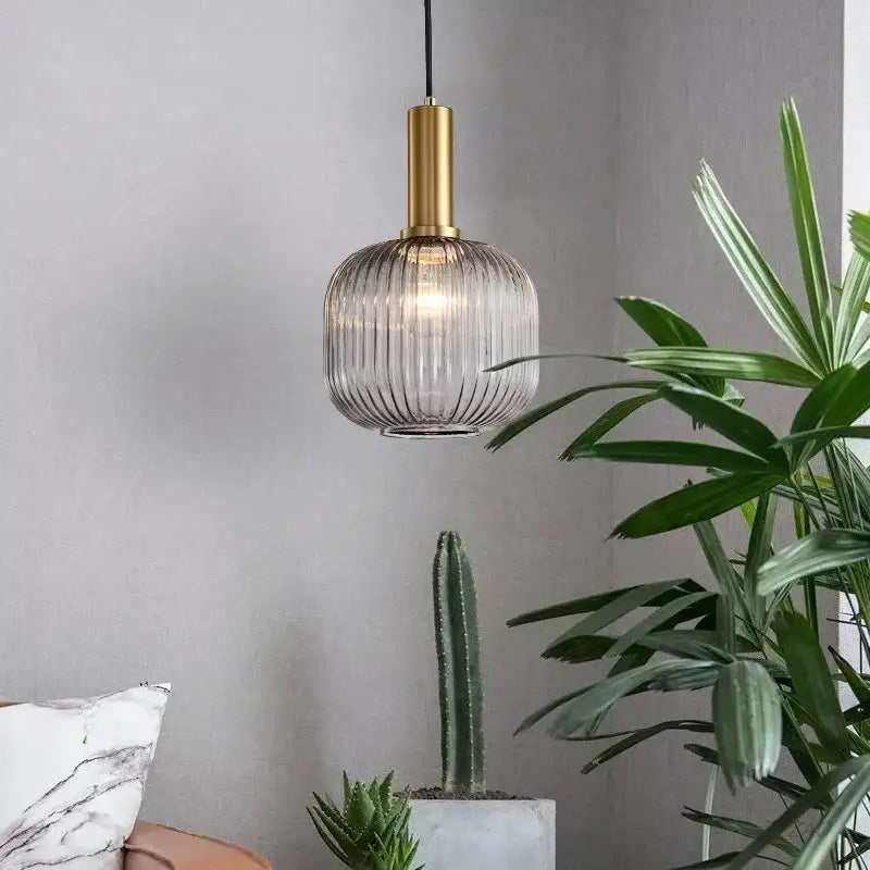 Elegant amber glass pendant lights with gold-finished metal stem and ribbed translucent shade for dining room ambiance