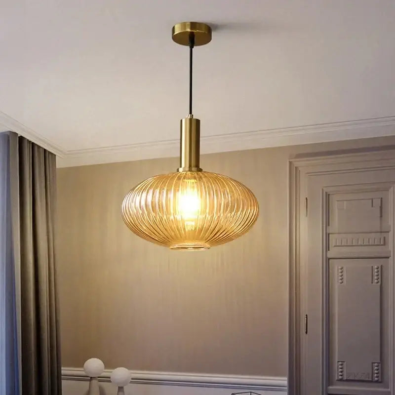 Elegant amber ribbed glass pendant light with brass-finished fixture and black cord perfect for dining room pendant lights
