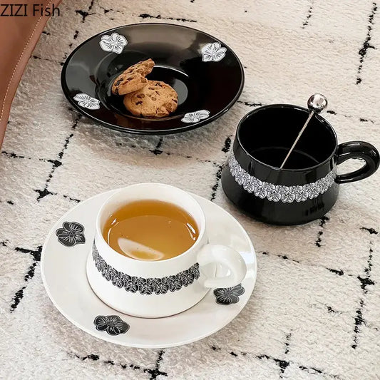 Black ceramic porcelain cup with white floral decals holding two chocolate chip cookies from elegant mug set