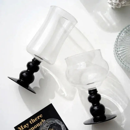 Two clear glass goblets with black bulbous stems and flat bases for elegant black goblet glass coffee use