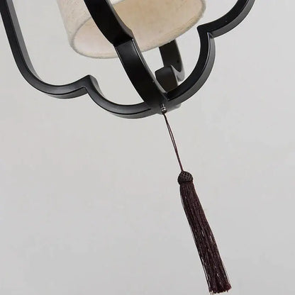 Elegant black wrought iron wall sconce lamp with beige fabric shade and dark brown tassel for bedroom lighting