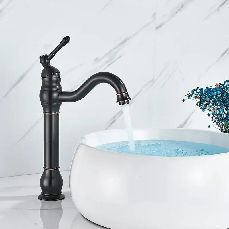 Elegant black matte single handle sink faucet with curved spout and ornate detailing beside white ceramic sink
