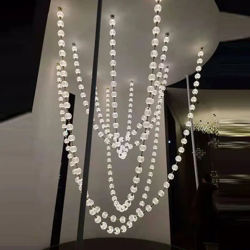 A modern decorbites elegant pendant chandelier with clear faceted glass beads and gold accents for staircase lighting