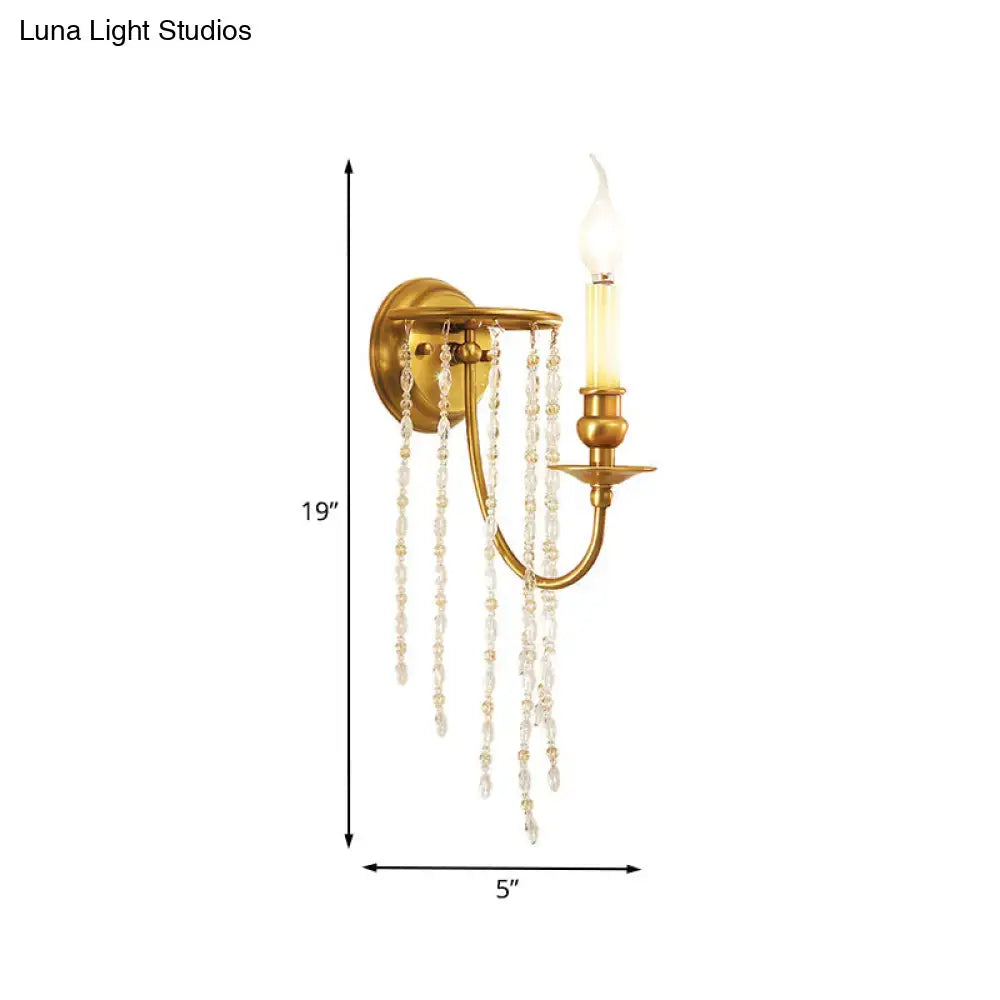 Gold-finished light fixture with a single candle bulb and cascading clear crystal chain gold strands for living room decor