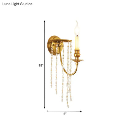 Gold-finished light fixture with a single candle bulb and cascading clear crystal chain gold strands for living room decor