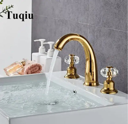 Gold basin faucet with decorbites crystal handle and curved spout mounted on white sink for bathroom use