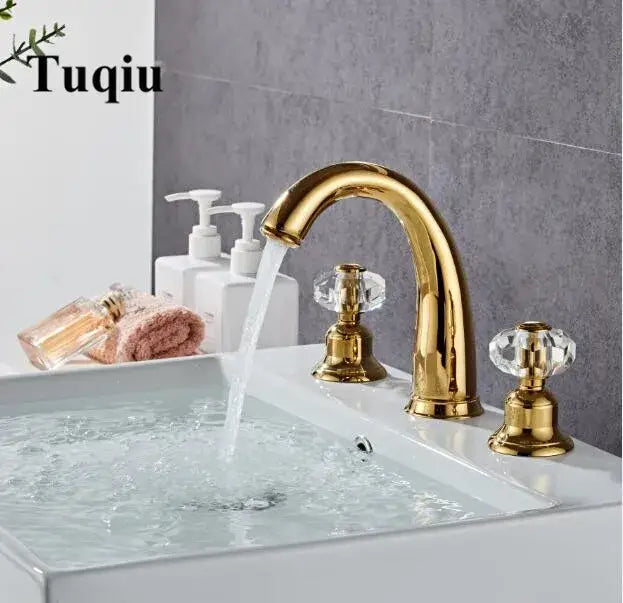 Gold basin faucet with decorbites crystal handle and curved spout mounted on white sink for bathroom use