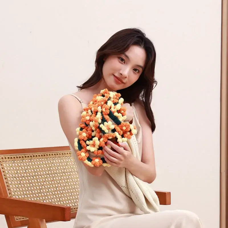 A handcrafted crochet floral clutch in vibrant orange and cream hues featuring an elegant daisy bouquet soft pattern
