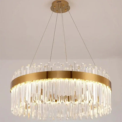 A modern elegant crystal chandelier pendant light with gold metal frame and cascading clear prisms for dining room decorbites