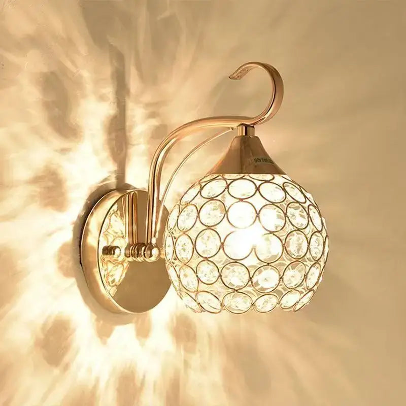 Elegant gold decorbites crystal wall sconce with spherical globe featuring circular cutouts and a curved arm for bedroom lighting