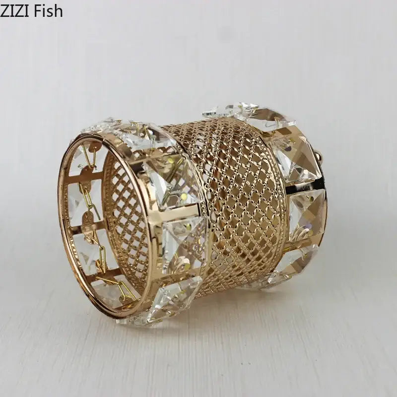 Elegant gold-toned bangle bracelet with mesh design and clear crystal accents beside hollow glass jar makeup brush holder