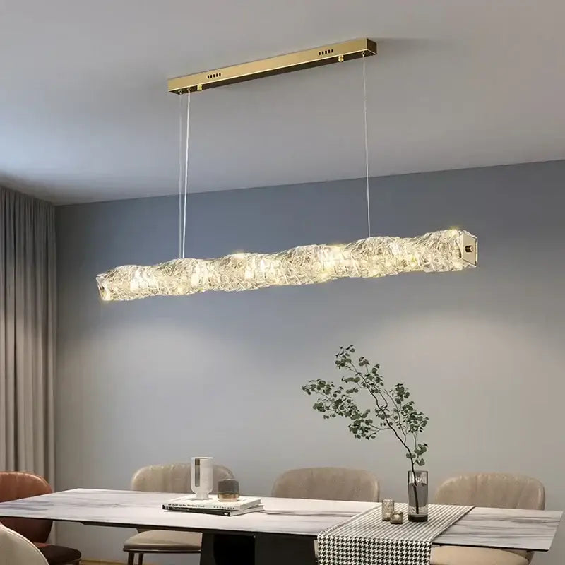 Elegant gold led crystal rectangular pendant light with textured crystal body illuminating dining room space