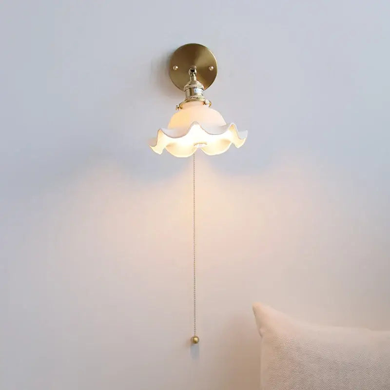 Elegant gold ceramic led wall light with a brass base and off-white scalloped glass shade by decorbites ceramic led wall