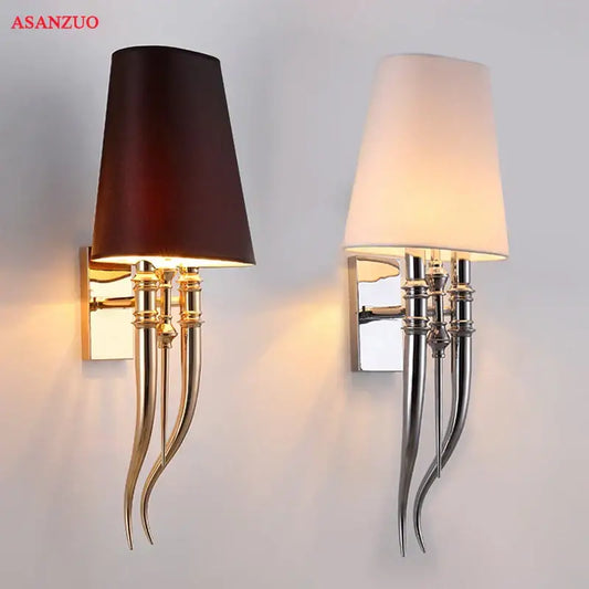 A pair of elegant gold and silver iron claw horn wall sconces with dark brown and off-white fabric shades on white background