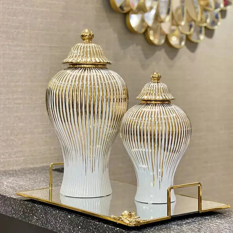 Elegant gold striped ceramic ginger jars with white finish and matching lids displayed on a mirrored tray for living room storage