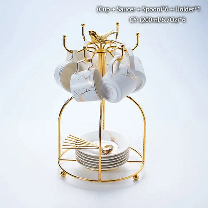Gold-toned metal cup rack with six white marble ceramic tea cups saucers and spoons in elegant ceramic tea set design