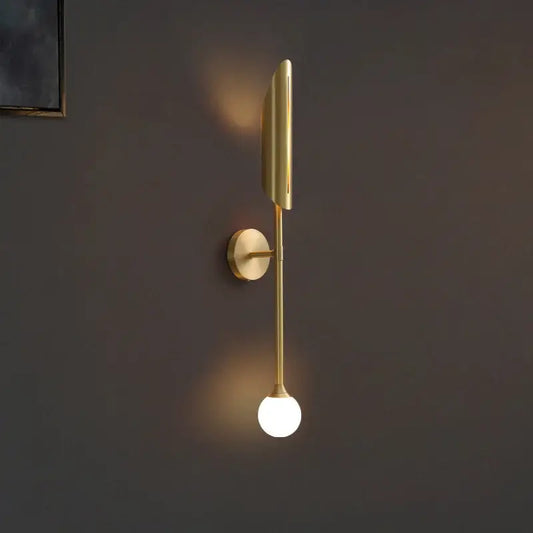 Gold-toned wall lamp with a sleek elongated design and frosted glass bulb by decorbites elegant modern wall decor