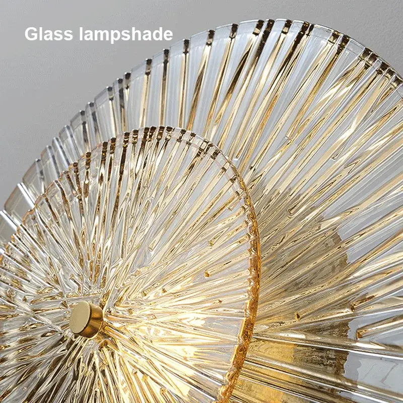Elegant glass wall sconces featuring clear ribbed glass lampshades with gold-trimmed fan-like segments by decorbites