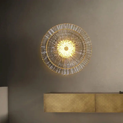 A radiant circular wall sconce with golden frame and ribbed glass segments for living room decorbites elegant glass wall