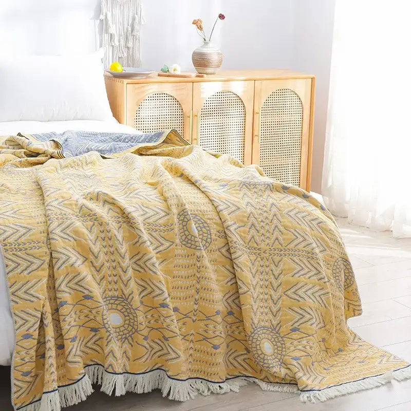 A soft yellow decorbites cotton gauze throw blanket with embroidered geometric patterns and white fringe edges