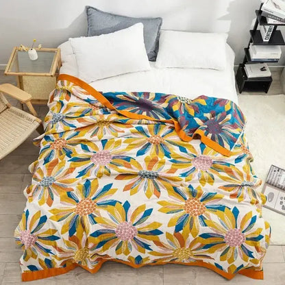 A vibrant embroidered floral blue and cream decorbites cotton gauze bedroom blanket with yellow blue and pink blossoms