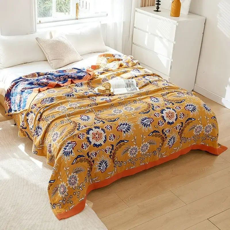 Vibrant mustard-yellow decorbites cotton gauze throw blanket with embroidered floral patterns in navy blue white and orange accents