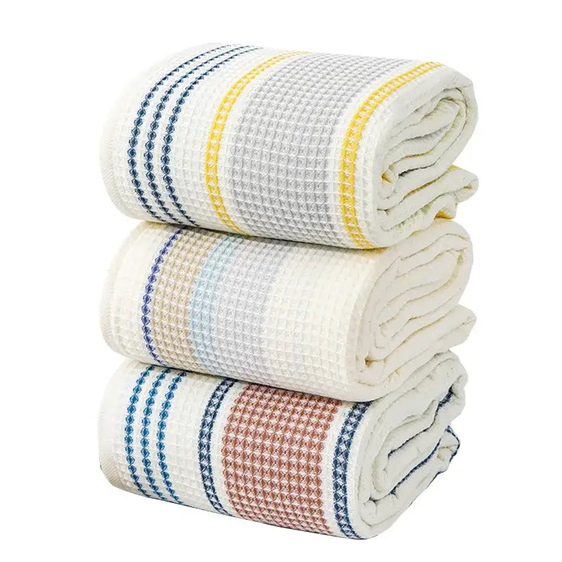 Stacked waffle-weave kitchen towels in cream blue and yellow stripes complement embroidered white and blue decorbites cotton bath towels