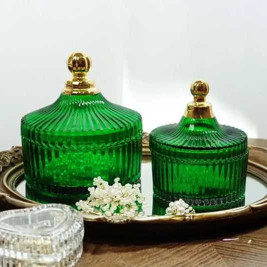 Two emerald green ribbed glass storage jars with gold-toned lids on a mirrored tray decorbites green striped jars