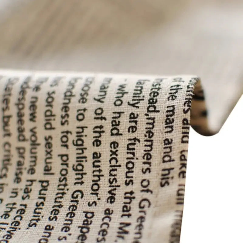 A close-up of an english newspaper style photography props kitchen placemat strip on textured off-white fabric background