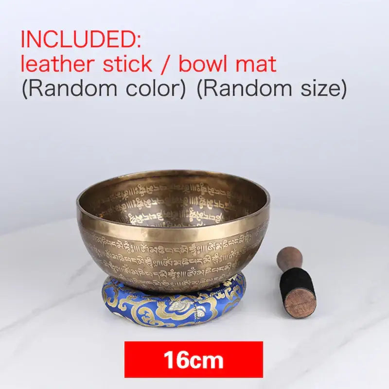 A 16cm bronze tibetan singing bowl with intricate engraved sanskrit script resting on a blue and gold cushion