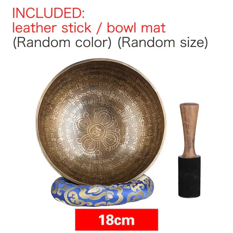 Bronze-colored engraved tibetan singing bowl with central floral design on ornate blue gold cushion for meditation