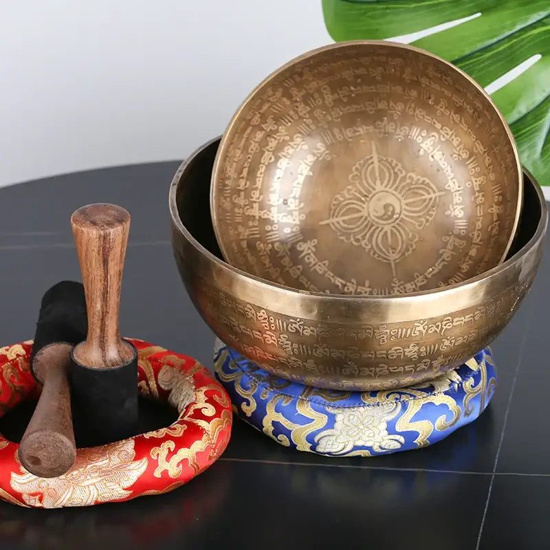 Golden tibetan singing bowl with intricate sanskrit inscriptions and lotus design on an ornate blue cushion for meditation