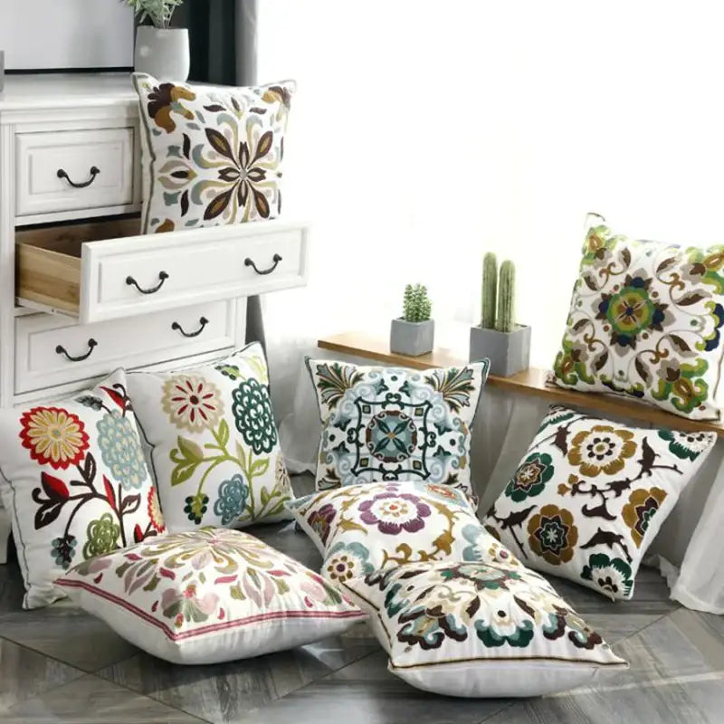 A collection of decorbites ethnic style embroidered pillow covers in vibrant floral and geometric patterns on white canvas