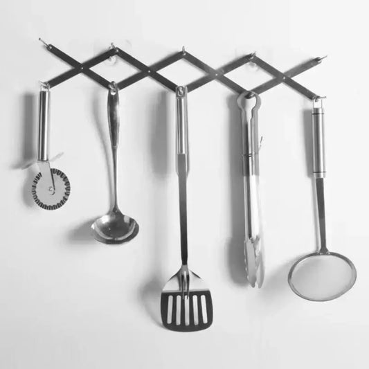 Expandable black stainless steel dish drying holder with five kitchen utensils hanging on a metal drying holder rack