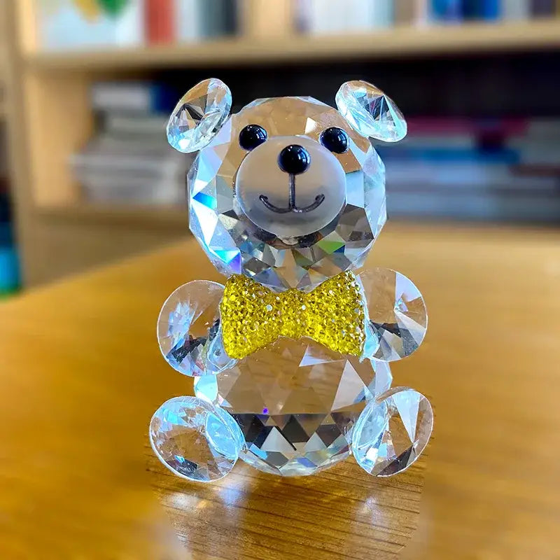 A faceted clear crystal teddy bear figurine with a transparent body and gold bow tie for bedroom decor