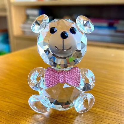 A faceted clear crystal teddy bear figurine with a pink bow tie and black button eyes for bedroom decor