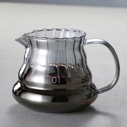 Clear glass coffee carafe with faceted diamond design, fluted rim, ribbed body, metallic base, and filter cup